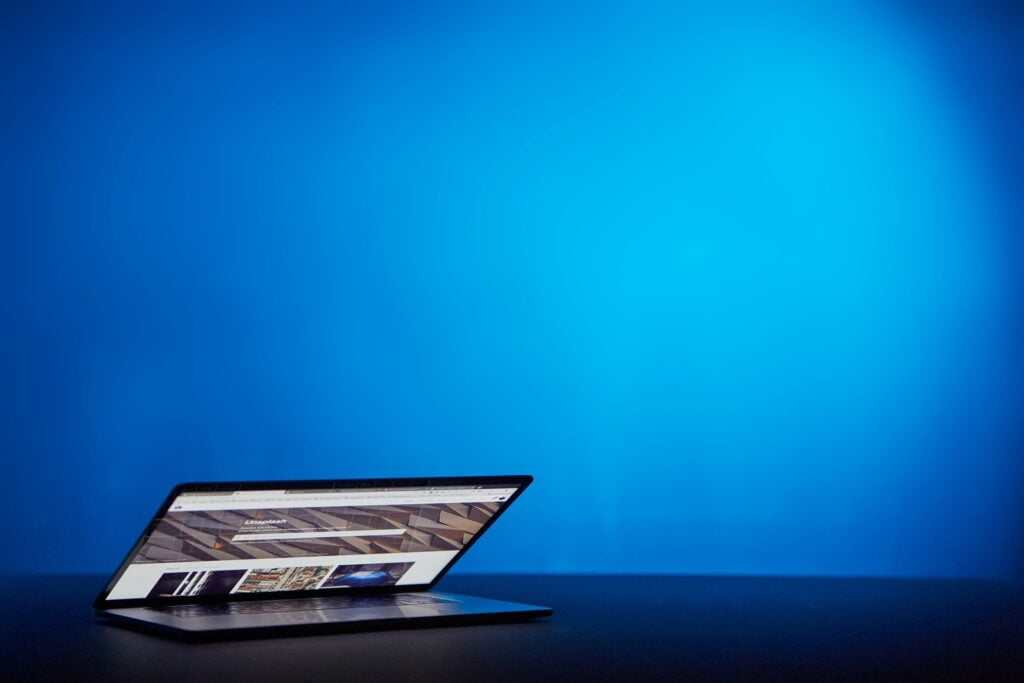Laptop die halfopen staat voor een blauwe achtergrond.